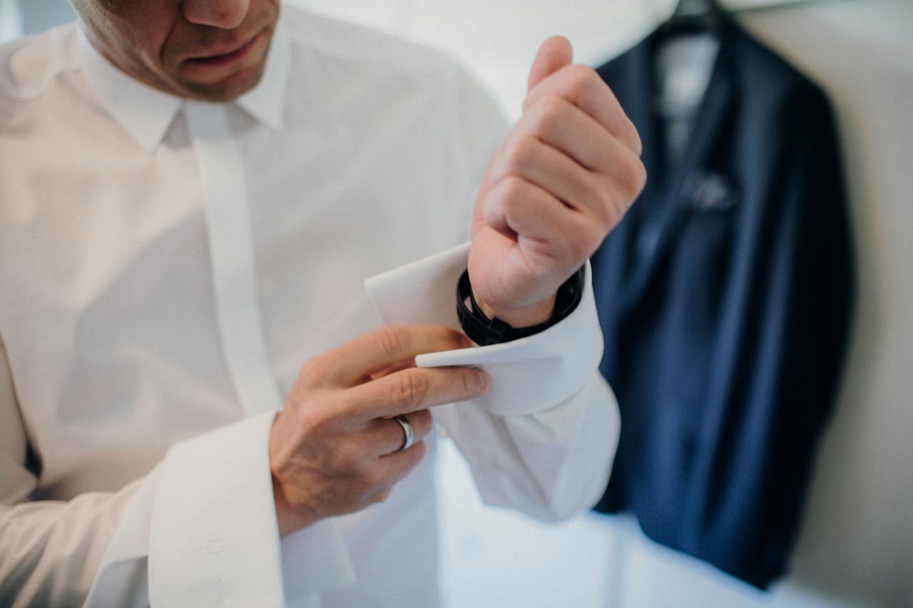 Close-up of a man adjusting his cufflinks, showcasing elegance and style in formal attire.