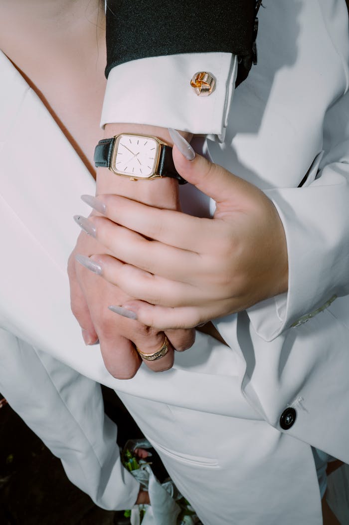 Stylish couple's hands in formal attire showcasing a luxury watch and nail art.